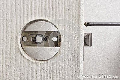 Install door latch with a screwdriver. Stock Photo