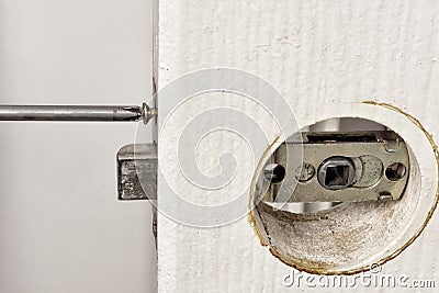 Install latch with a screwdriver on the door. Stock Photo