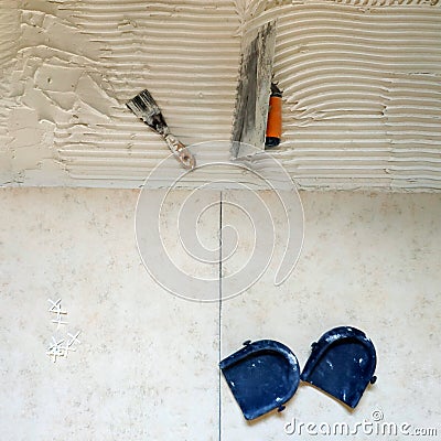 Installation of ceramic tiles. Tools for laying tiles- trowel, toothed spatula, plastic crosses, knee pads. Stock Photo