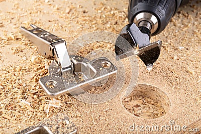 Installation of furniture hinges in chipboard. Small carpentry work in the workshop Stock Photo