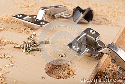 Installation of furniture hinges in chipboard. Small carpentry work in the workshop Stock Photo