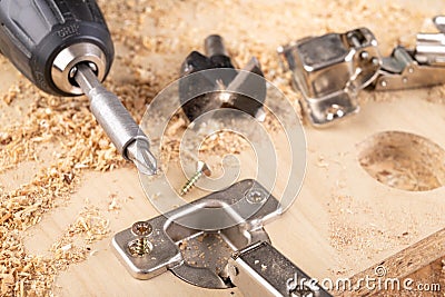 Installation of furniture hinges in chipboard. Small carpentry work in the workshop Stock Photo