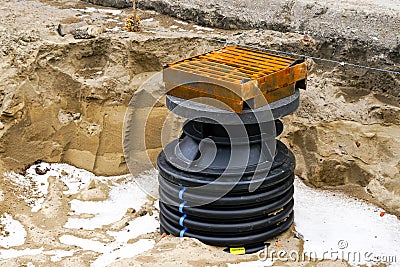 Installation of a new modern plastic rainwater drainage well with cast iron grate in the city street Stock Photo