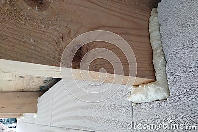 Installation of wooden beams of roof frame with spray foam on a house wall under construction Stock Photo