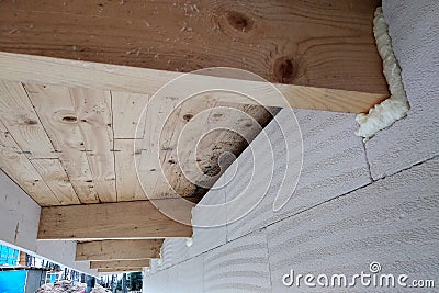 Installation of wooden beams of roof frame with spray foam on a house wall under construction Stock Photo