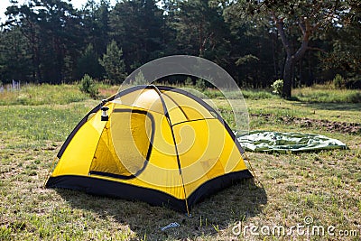 Installed tourist tent and a camping lantern in nature in the forest. Domestic tourism, active summer holidays, family adventures Stock Photo