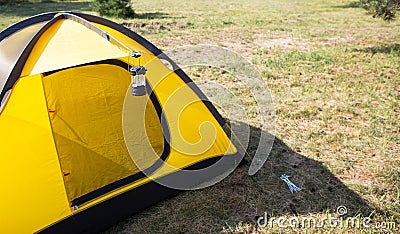 Installed tourist tent and a camping lantern in nature in the forest. Domestic tourism, active summer holidays, family adventures Stock Photo