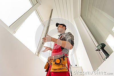 The installer worker in safe medical mask and overalls fixes a detail of the stiffener element with screws using an Stock Photo