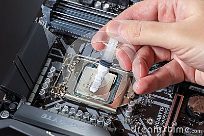 A technician applies white thermal paste to the CPU Intel i7-9700K. Installing a cooler on a PC processor. Assembling or Editorial Stock Photo
