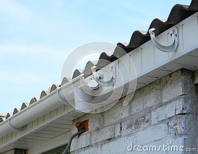 Installing plastic roof gutter holder for dowspout drain pipe outdoor. Plastic roof guttering, rain guttering Stock Photo