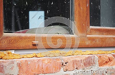 Installing plastic window in brick house with caulking gun foam Stock Photo