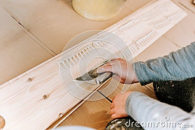 Worker installing wooden hardwood floor, detail on man hands holding wooden tile and spreading glue Stock Photo