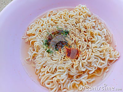 Instant noodle in a pink bowl with some seasoning ingredient Stock Photo