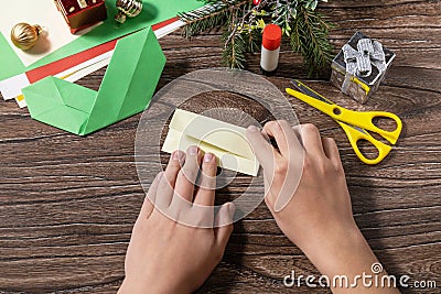 Instruction step 7. Christmas greeting card gift origami candle on wooden table. Childrens art project, handmade, crafts for kids Stock Photo