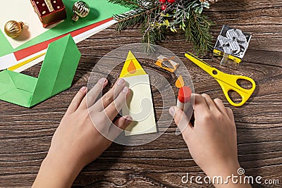 Instruction step 10. Christmas greeting card gift origami candle on wooden table. Childrens art project, handmade, crafts for kids Stock Photo