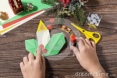 Instruction step 12. Christmas greeting card gift origami candle on wooden table. Childrens art project, handmade, crafts for kids Stock Photo