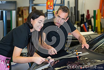 Instructor and apprentice in car wrapping workshop Stock Photo