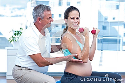 Instructor assisting cheerful pregnant woman Stock Photo