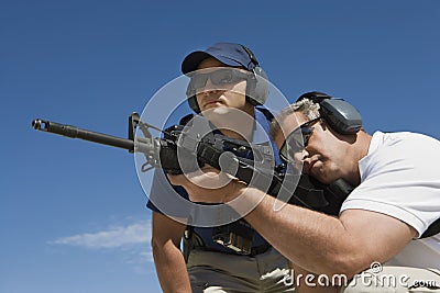 Instructor With Man Aiming Machine Gun Stock Photo