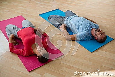 Instructor with student practicing reclined hero pose in yoga studio Stock Photo