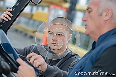 Instructor teaching apprentice how to drive heavy construction vehicle Stock Photo