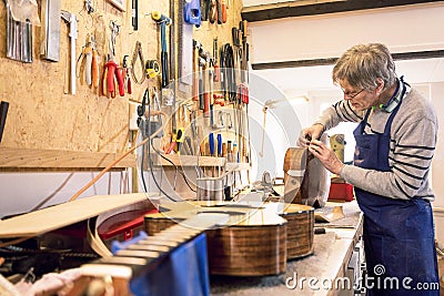 Instrument maker repairing an old acoustic guitar Stock Photo