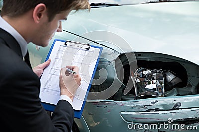 Insurance agent examining car after accident Stock Photo