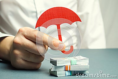 An insurance agent holds a red umbrella over dollar bills. Savings protection. Keeping money safe. Investment and capital Stock Photo