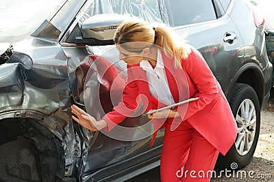 Insurance agent with tablet inspecting broken car Stock Photo