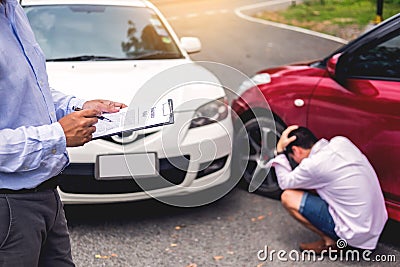 Insurance agent writing on clipboard while examining car after accident claim being assessed and processed Stock Photo