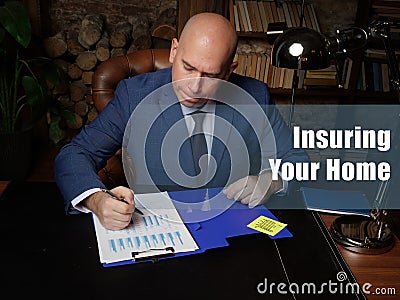 Insuring Your Home inscription. Male office workers with yellow shirt holding and writing documents on office desk Stock Photo