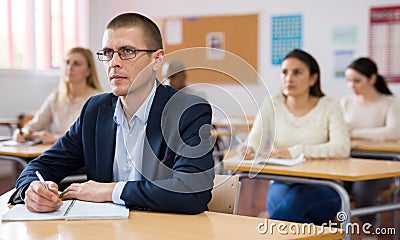 Intelligent adult man in glasses listening to lecture in classroom Stock Photo