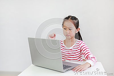 Intend asian little child sitting at desk and using laptop at home Stock Photo