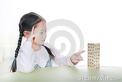 Intend little Asian child girl thinking to playing wood blocks tower game for Brain and Physical development skill in a classroom Stock Photo