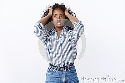 Intense african american curly-haired woman panic holding hair widen eyes gasping shocked made huge mistake standing Stock Photo