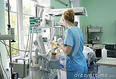 At the intensive care unit. Nurse standing near hospital bed with a baby preparing it for treatment Editorial Stock Photo