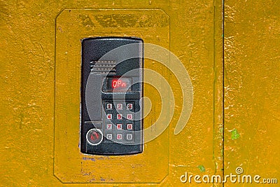 An intercom on old painted yellow steel surface with a keypad, digital display and rfid sensor for calling close-up Stock Photo