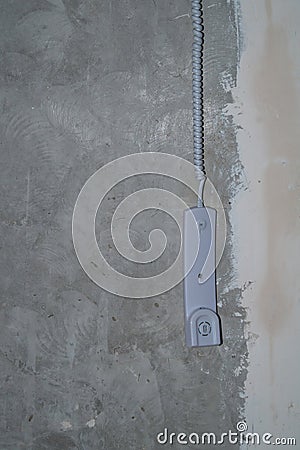 Intercom phone receiver on gray concrete background. handset hanging on the wire Stock Photo