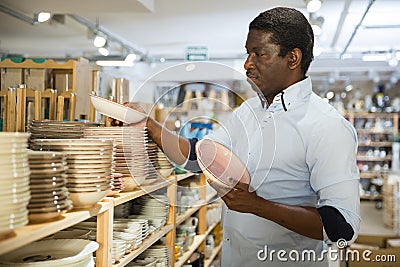 Interested african american man choosing plates in dishware store Stock Photo