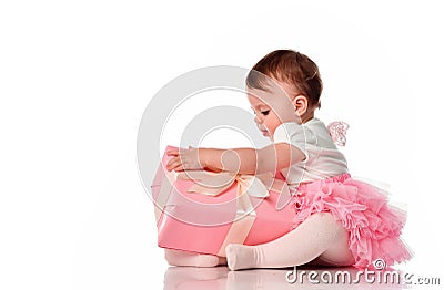 Interested baby girl try unpack gift box studio shot Stock Photo