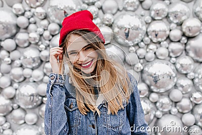 Interested beautiful girl in denim jacket touching her long hair. Smiling european female model in Stock Photo