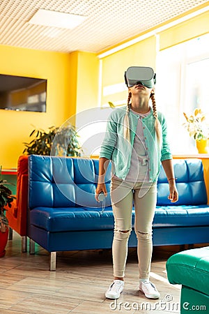 Interested schoolgirl getting acquainted with virtual reality. Stock Photo