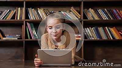 Interested schoolgirl plays online game on tablet in library Stock Photo