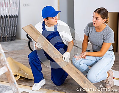 Young woman talking to builder during laminate flooring installation in apartment Stock Photo