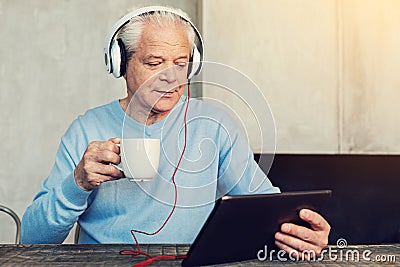 Progressive pensioner watching film on his tablet Stock Photo