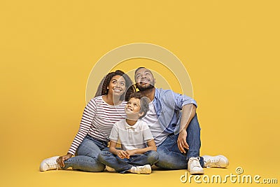 Interesting Offer. Smiling Black Family Of Three Looking Upwards At Copy Space Stock Photo