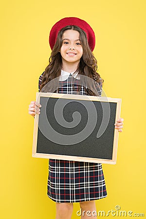 Interesting school lesson. Little child holding blank blackboard for private lesson on yellow background. Cute pupil Stock Photo