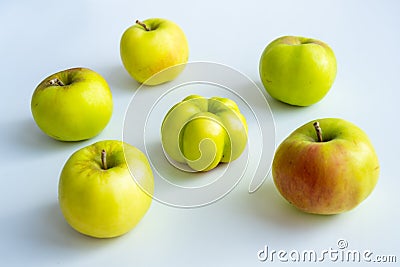 An interesting, unusual, strange apple. An ugly apple surrounded by ordinary ones. The photo symbolizes individuality, leadership Stock Photo