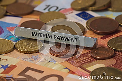 interim payment - the word was printed on a metal bar. the metal bar was placed on several banknotes Stock Photo
