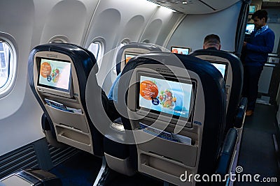 The interior of the aircraft. Empty airplane cabin. Rows of passenger seats with screens in the head restraints Editorial Stock Photo